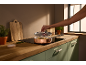 Modern kitchen with a copper pan on an induction hob, a hand lifting the lid.
