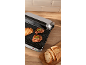 Electric grill with steaks and toasted bread, with fresh bread on the side.