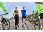 Man and woman in sportswear walking on a trail, with cyclists beside them.
