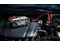 Car battery charger with jump leads connected to the engine