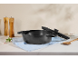 Cast iron pot with lid, wooden spice grinders, and kitchen utensils on a table.