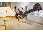 A cordless angle grinder cuts a metal pipe, with sparks flying.