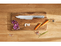 Chef's knife with chopped vegetables and spices on a wooden table.