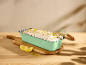 Loaf pan with lemon cake topped with pistachios on a wooden cutting board.
