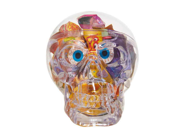 Transparent skull filled with colorful candies and paper eyes, on a black background.