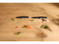 Two black knives on a wooden surface with chopped vegetables and spices.