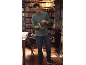 Man in a green long-sleeve t-shirt and jeans reading a book in a library.
