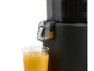 Fresh orange juice flowing from a juicer into a glass.