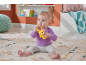A baby sitting on a rug, playing with a yellow bear-shaped rattle.