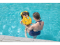 Mother and child in a yellow life vest in a swimming pool.