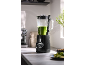 Black blender with green smoothie on a kitchen countertop.