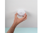 Man installing a white smoke detector on the ceiling.