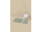 Two green striped bath mats in a bathroom with a wall-mounted toilet.