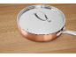 Copper pan with a stainless steel lid on a wooden surface.