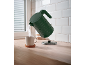 Green kettle pouring hot water into a mug on a wooden countertop.