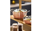 Two copper-colored pots and glass jars on a wooden shelf.