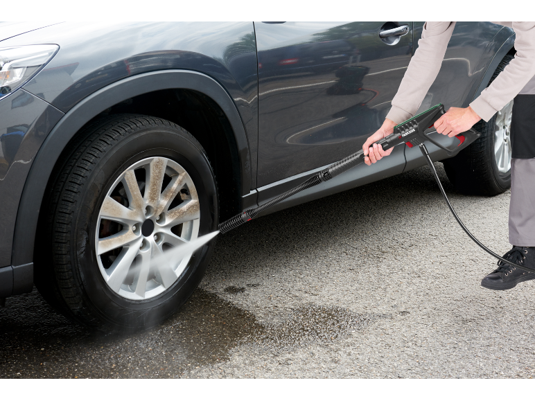 Man cleaning a car wheel with a pressure washer.