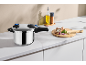 Metal pressure cooker with fresh ingredients on a kitchen counter.