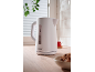White electric kettle on a wooden countertop with a cup of tea and cookies.