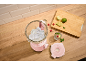 Pink blender with ice, glass pitcher, fruits, and wooden cutting board.