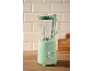 Green jug blender with a wooden base and white tiles in the background