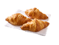 Three golden-brown croissants on a white napkin, ready to be enjoyed.