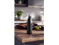 Black thermal bottle on a kitchen table, with green limes and brown fabric in the background.