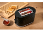Black toaster with toast, jam, and a wooden cutting board.