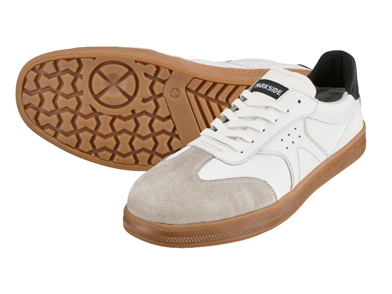White and beige sneakers with a brown rubber sole, one turned over to show the sole.