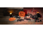 Halloween decorations with pumpkins, bats, candles, and a bottle on a wooden table.