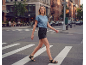 Woman in sandals and black shorts crossing a crosswalk in the city.