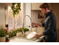 Man washing dishes in a kitchen decorated with Christmas garlands and a nutcracker.