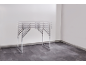 Aluminum folding table with adjustable legs in an empty room.