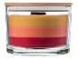 Layered candle in a glass jar with a wooden lid, featuring yellow, orange, and red wax.