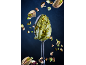 Spoon with pistachio cream and floating pistachios against a dark background.
