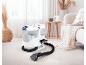Carpet cleaner in a bright living room with a beige rug and sofa.