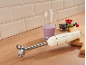Cream hand blender with berry smoothie and fruits on a wooden countertop.