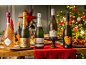 Five bottles of sparkling wine, champagne, and prosecco on a Christmas table with festive decor.