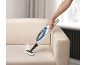Handheld steam cleaner cleaning a beige sofa, with steam rising from it.
