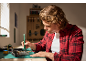 Man repairing electronics with a precision screwdriver in a workshop setting.