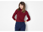 Woman in a burgundy ribbed turtleneck and dark blue trousers, hands on hips.