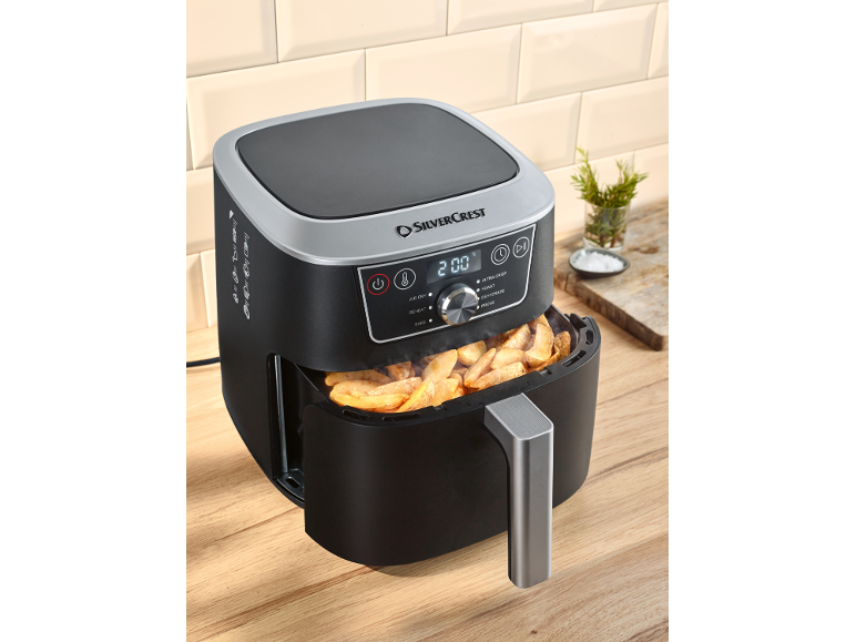 Black air fryer with a digital display showing '200' and a basket full of potato wedges.