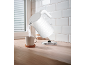 White kettle pouring hot water into a mug on a wooden countertop.