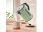 Green kettle pouring hot water into a mug on a wooden countertop.