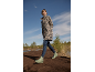 Woman in leopard print jacket and green wellington boots walking on a peat path.