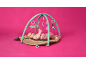 Baby lies on a play mat with arches, playing with hanging toys.