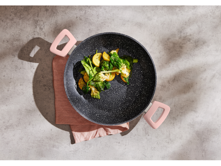 Frying pan with vegetables on a gray background with a pink napkin
