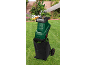 Garden shredder with collection bag, processing branches in a garden.