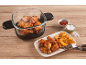 Chicken wings and potato wedges in a glass container and on a plate with sauces.