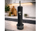 Black beverage dispenser on a marble kitchen counter with a blurred background.